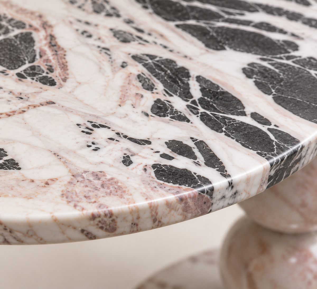 Macro detail of the Three-Lobed Pedestal Side Table stone top and edge with grey, black, white and pink veining.