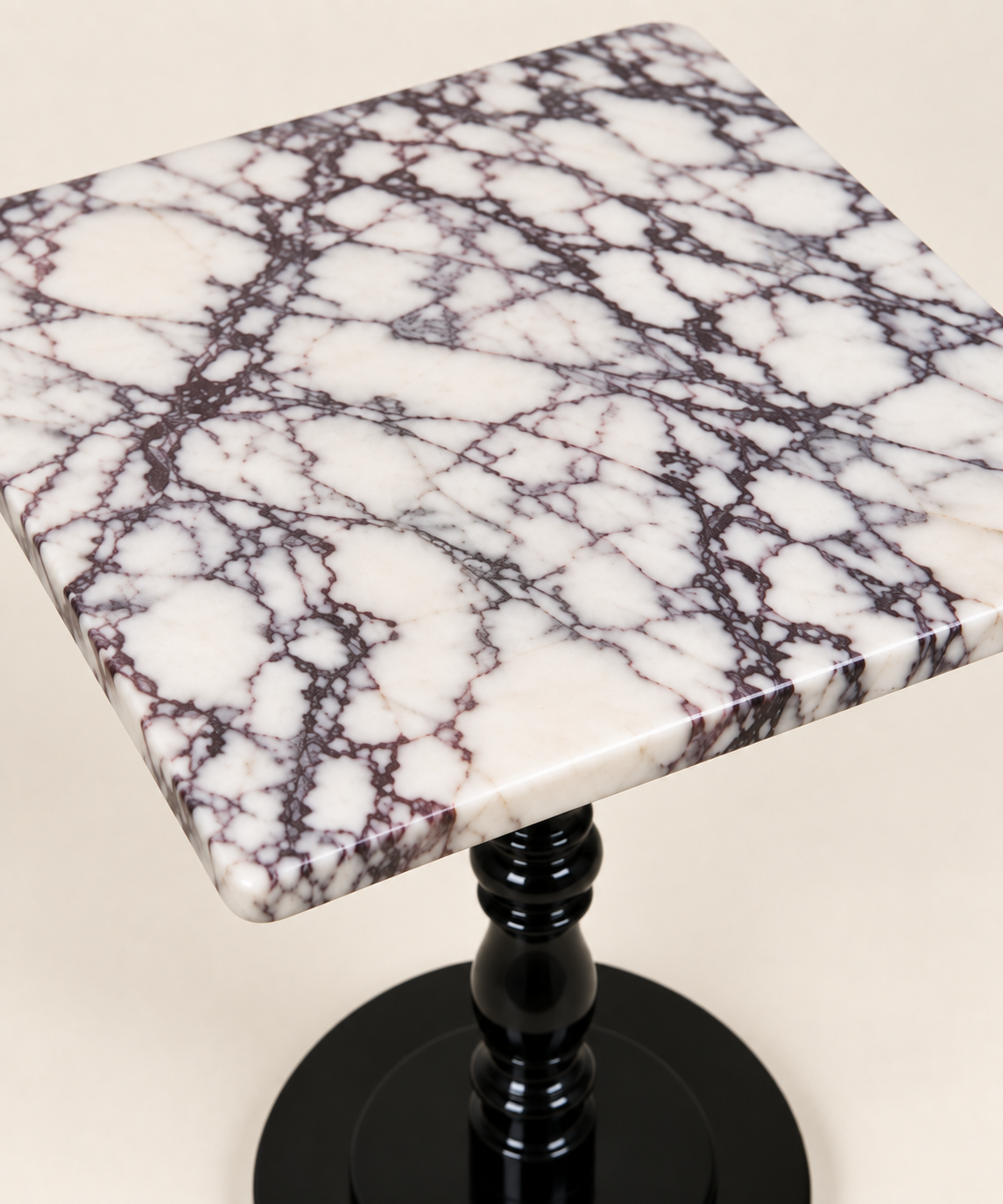 Calacatta Viola square tabletop detail showing the top surface, edge thickness and glossy black pedestal below.
