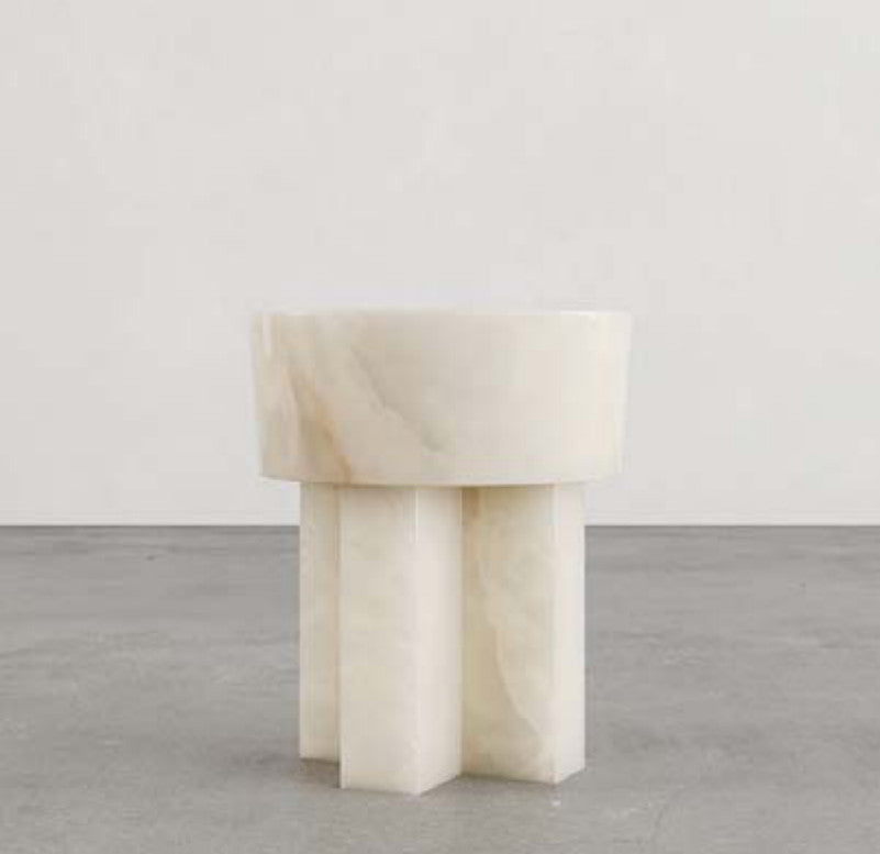 Cream-coloured stone side table with a thick round top and intersecting slab legs