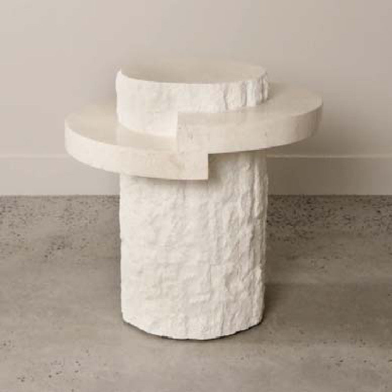 Pale stone side table with a stepped circular top and rough-textured cylindrical base