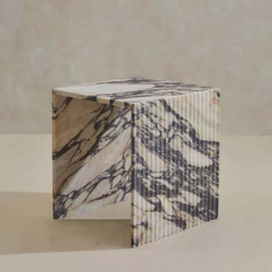 A compact Calacatta Viola side table with a bridge-like profile and vertically fluted sides.