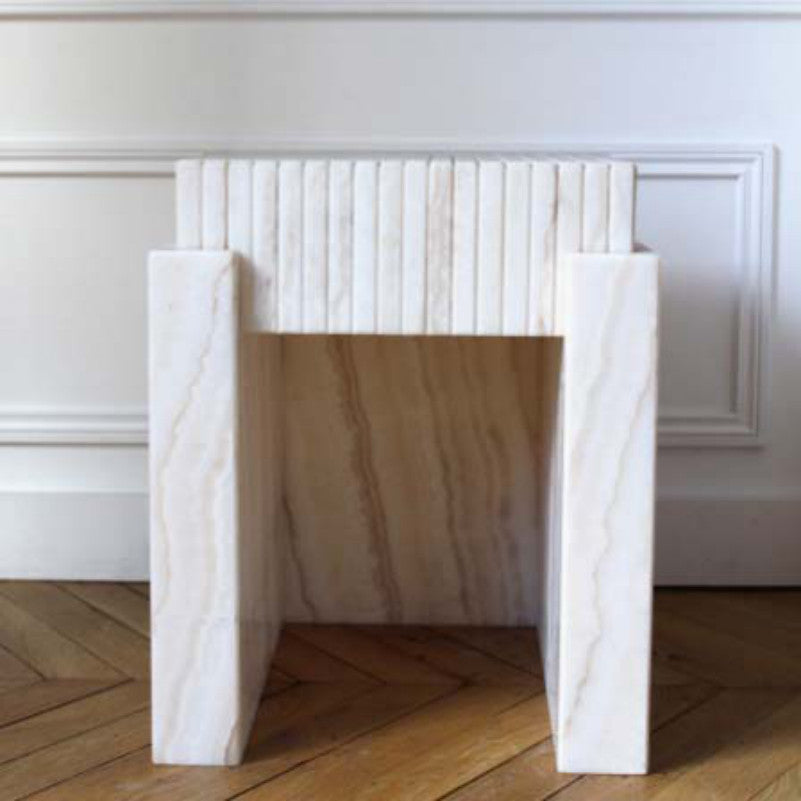 White and beige stone side table with straight slab sides and a vertically ribbed raised back