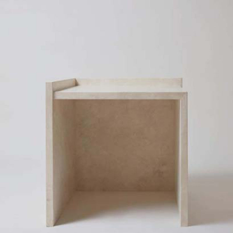 Pale stone side table with a square top, straight slab sides and raised back edge