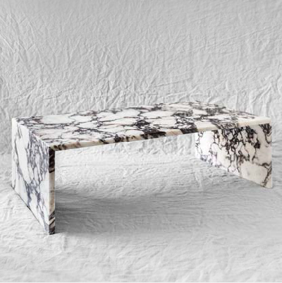 A low Calacatta Viola coffee table with a slim bridge profile and a continuous stone pattern across the top and sides.