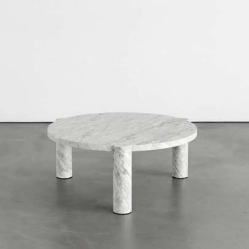 White and grey-veined stone coffee table with a round top and three cylindrical legs