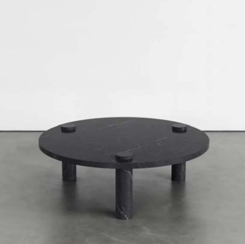 Black veined stone coffee table with a round top, three cylindrical legs and raised circular details
