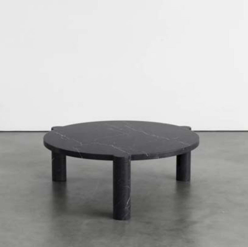 Black veined stone coffee table with a round top and three cylindrical legs