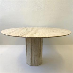 Round beige stone dining table with a grooved pedestal, three-quarter view