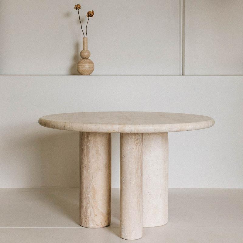 Round beige stone dining table with clustered cylindrical supports, front view