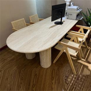 Oval stone dining table with fluted supports and wooden chairs, viewed from above
