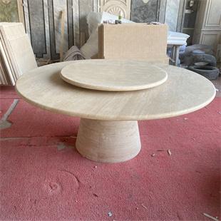 Round beige stone dining table with a raised circular centre and tapered pedestal in a workshop