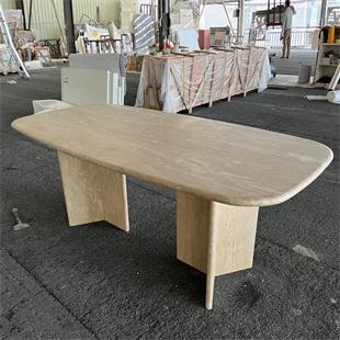Rectangular pale stone dining table with rounded corners and two slab supports in a workshop