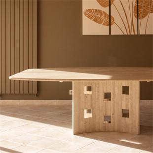 Pale stone dining table with square openings in its slab support, cropped side view