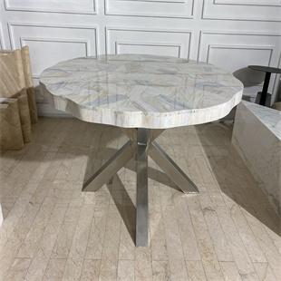 Stone dining table with a lobed top and angular intersecting supports, three-quarter view