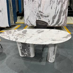 Oval pale veined stone dining table with two contrasting supports in a showroom