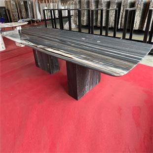 Rectangular dark striped stone dining table with two slab supports in a workshop