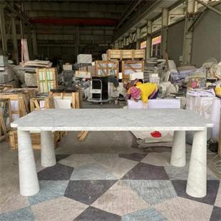 Rectangular pale stone dining table with four cylindrical legs in a workshop