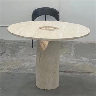 Round pale stone dining table with a central opening and cylindrical pedestal