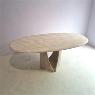 Oval beige stone dining table with an open angular pedestal, three-quarter view