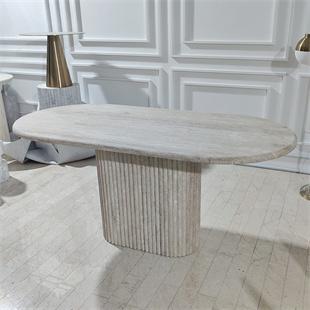 Oval pale stone dining table with a fluted pedestal in a dining room