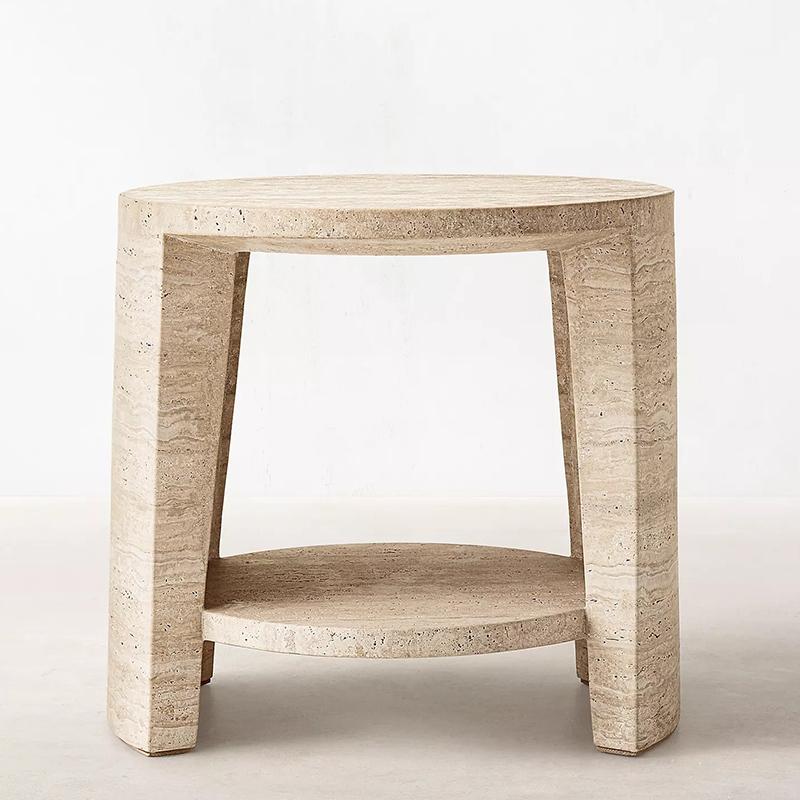 Round pale stone side table with an open lower shelf and three legs, front view