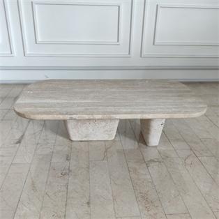 Pale stone coffee table with an elongated rounded top and two tapered supports