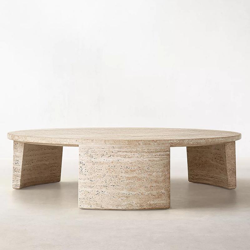 Round pale stone coffee table with broad slab supports, low-angle view