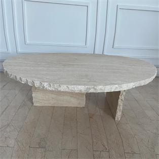 Oval pale stone coffee table with a rough-textured edge and slab supports on a wooden floor