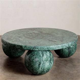 Round green veined stone coffee table with three spherical supports against a plain wall
