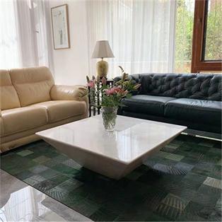 Square pale stone coffee table with sloping sides between two sofas
