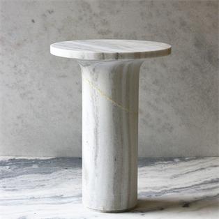 Round pale veined stone side table with a narrow pedestal, three-quarter view