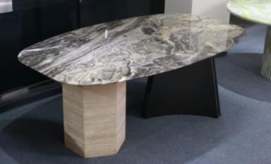Organic stone dining table with a grey veined top and two contrasting supports, three-quarter view